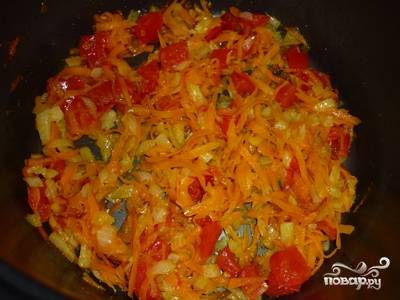 Очищенный лук мелко нашинкуйте, очищенную морковь потрите на крупной терке. Помидор нарежьте небольшими кубиками. Порезанные овощи выложите в чашу мультиварки и обжаривайте (режим "Выпечка") на растительном масле в течение 10 минут.