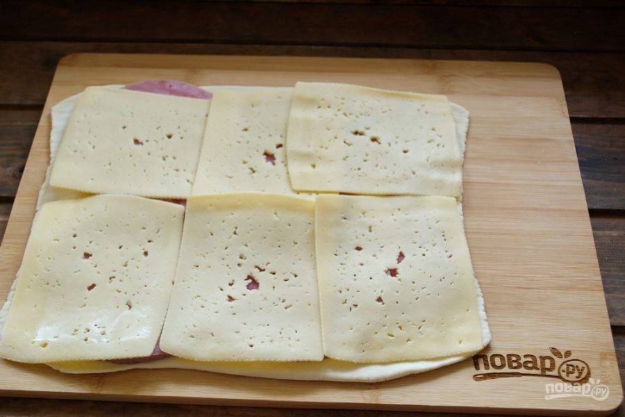 Возьмите сыр. В продаже имеются упаковки, когда сыр нарезан на пластины. Вместо твердого сыра можно взять пластинки плавленого бутербродного сыра типа "Хохланд". Ветчину накройте пластинками сыра.