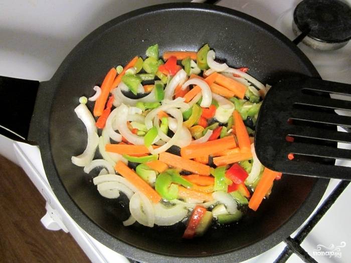 2. На сковороде разогрейте немного оливкового масла. Очистите и нарежьте лук, морковь, чеснок и сладкий перец. Выложите овощи на сковороду и обжарьте на среднем огне. Помидоры очистите от кожуры (сделайте надрезы и ошпарьте кипятком) и измельчите. 