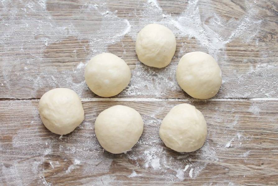 Разделите подошедшее тесто на одинаковые кусочки и сформируйте шарики. Накройте тесто тканью и дайте постоять 10 минут.