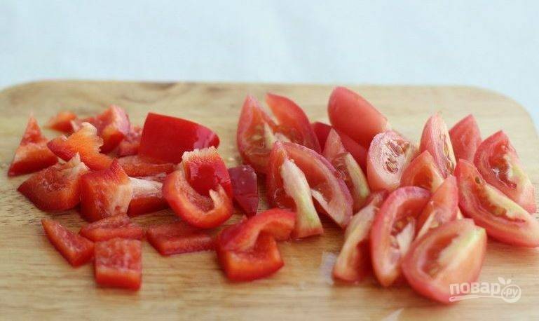 Вымойте сладкий красный болгарский перец и помидоры. Нарежьте томаты дольками. Перец очистите от семян и сердцевины, нарежьте его кубиками. 