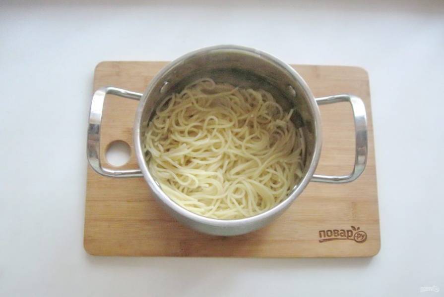 Сварите спагетти по инструкции на упаковке. После воду слейте и выложите макароны в кастрюлю.