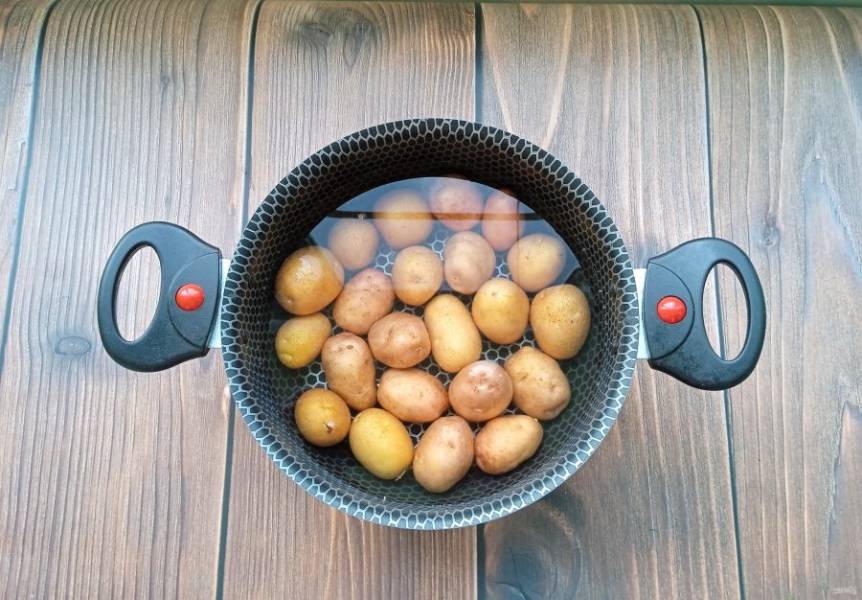 Мелкий молодой картофель тщательно помойте и выложите в кастрюлю. Залейте водой, немного посолите и поставьте на плиту.