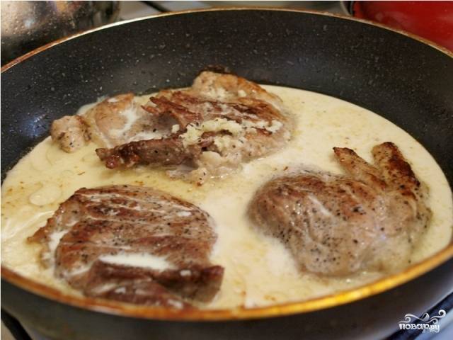 Когда мясо обжарится с обеих сторон, уменьшаем огонь под сковородкой и заливаем мясо приготовленным соусом. Закрываем сковороду крышкой, тушим мясо минут 8-10.