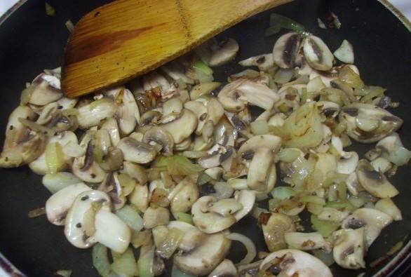 Ставим сковороду на огонь и растапливаем в ней сливочное масло. Выкладываем в масло нарезанный мелко лук и чеснок, жарим все до золотистого цвета. Далее добавляем к луку и чесноку нарезанные на небольшие кусочки грибы, продолжаем все жарить, пока из грибов не испарится практически вся жидкость, готовую начинку следует посолить и поперчить по вкусу.