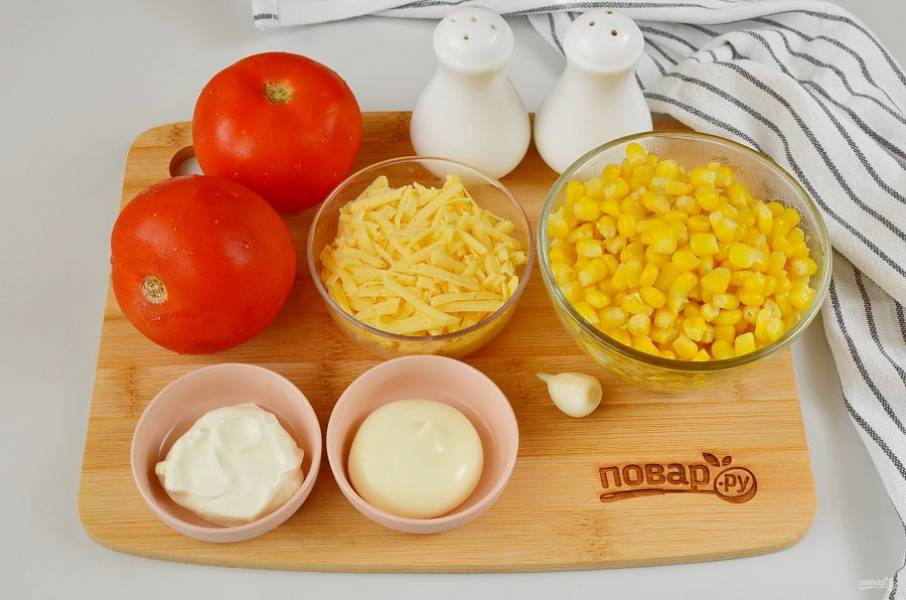 Подготовьте ингредиенты для салата. Помидоры вымойте, с кукурузы слейте всю жидкость. Очистите чеснок, натрите сыр.