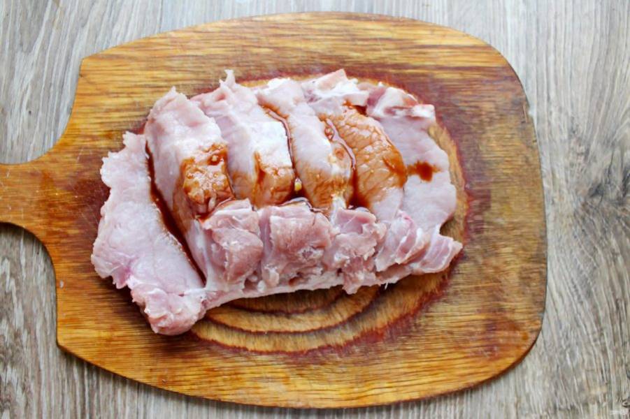 Свинину вымойте и обсушите бумажным полотенцем. Разрежьте мясо на стейки толщиной два сантиметра, не прорезая до конца. Смажьте маринадом все куски изнутри и снаружи.