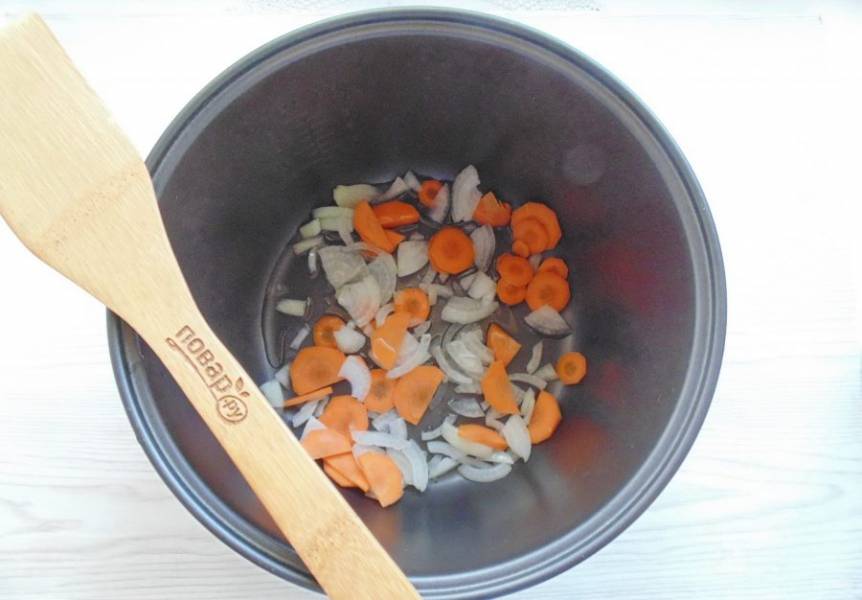 Морковь очистите и нарежьте кружками. Лук очистите, ополосните и нарежьте полукольцами. Выложите в чашу мультиварки. Влейте подсолнечное масло и в режиме "Жарка" обжарьте овощи 5-7 минут до прозрачности.