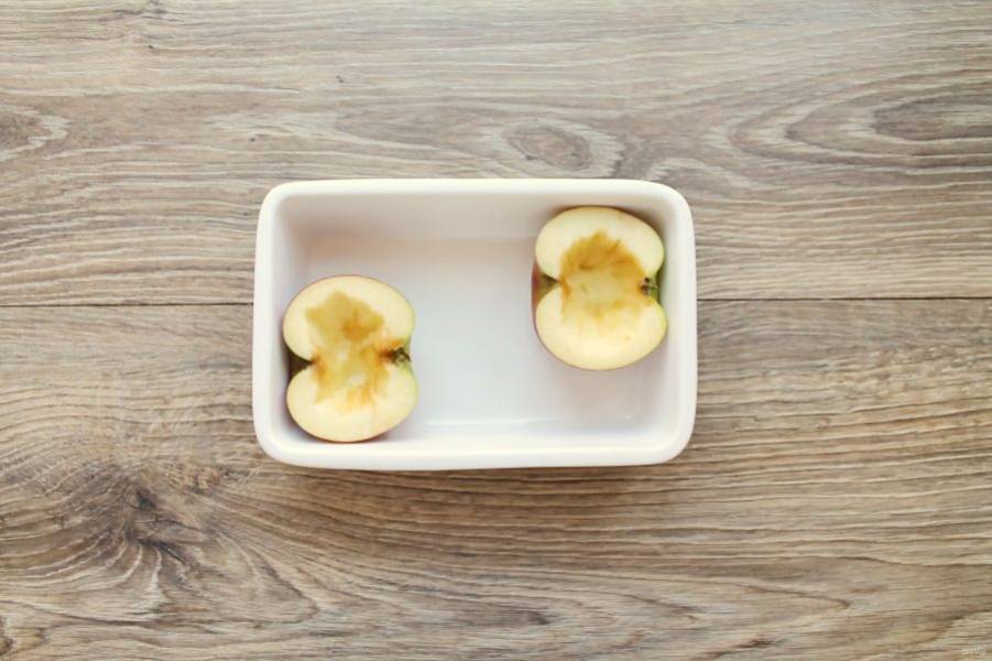 Яблоко вымойте, обсушите и разрежьте на две части. Удалите сердцевину, выложите в форму для запекания.