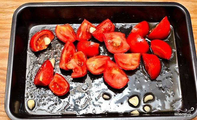 На противень положить порезанные на четвертинки помидоры и чеснок.