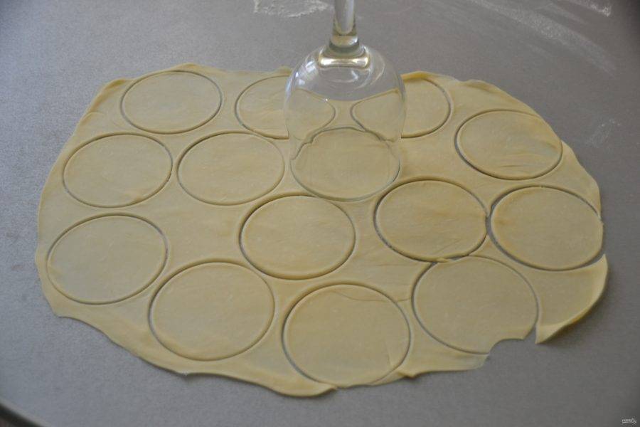 Тонко раскатайте в пласт тесто и вырежьте кружочки теста стаканом или бокалом.