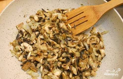 Обжарьте измельченный лук до прозрачности. Затем добавьте к нему нарезанные пластинами грибы, обжаривайте 6-7 минут. Не забудьте посолить.