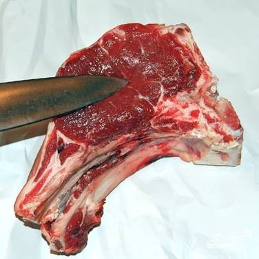 Берем кусок говядины, можно - с костью. Нам нужно вырезать нежное мясо - кусочек, на который я на этой фотографии указываю ножом. Оставшиеся кости можно будет использовать для приготовления бульона.
