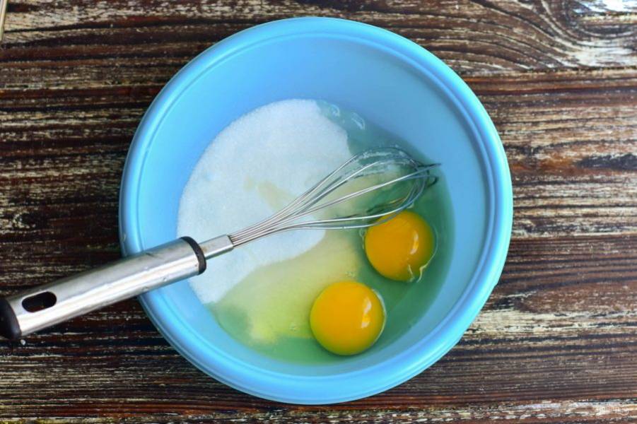 В миску вбейте куриные яйца и всыпьте к ним сахар.
