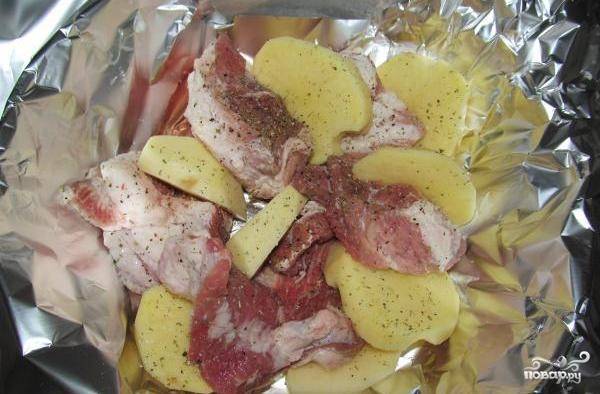 Картофель чистим и нарезаем на ваше усмотрение, мне, например, больше нравится дольками. Выкладываем картофель к мясу, солим и посыпаем сушеной зеленью и перцем. 