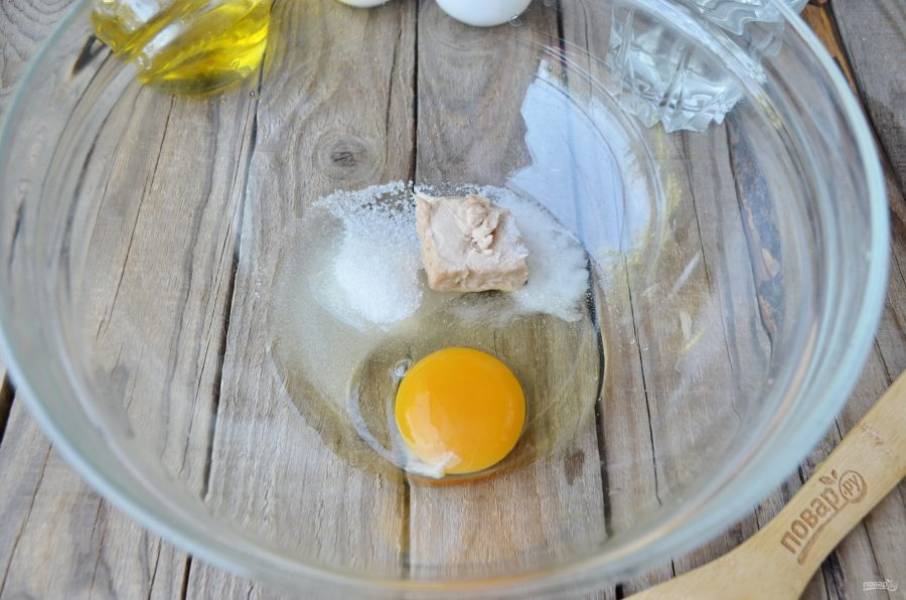 Пока капуста тушится, займемся тестом. Возьмите глубокую миску, положите в неё свежие дрожжи, сахар и соль, вбейте яйцо.