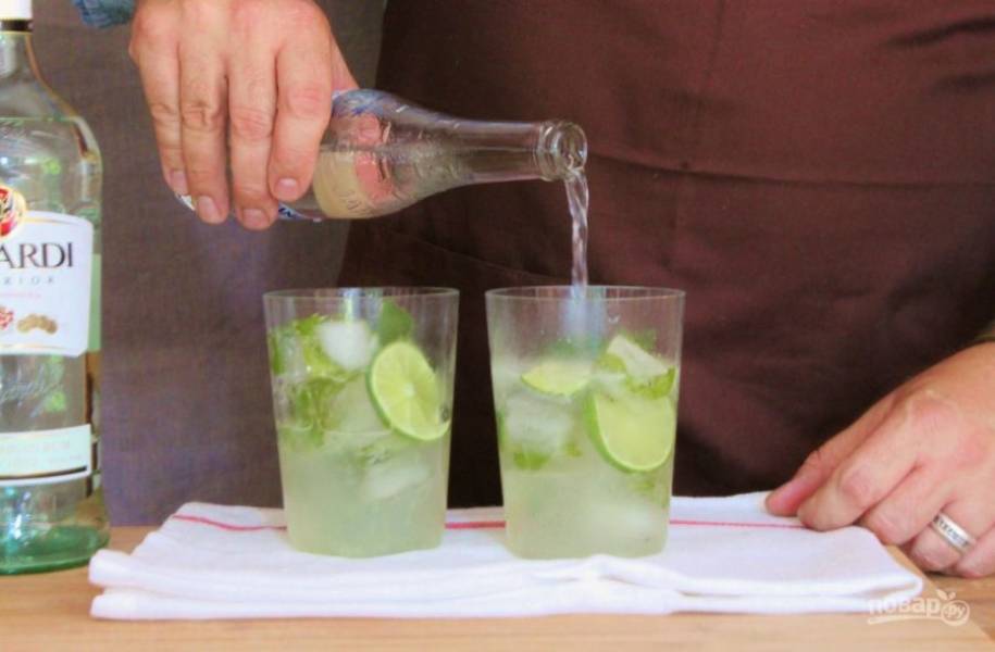 Разделите коктейль поровну на два стакана, добавьте застывшие кубики льда и налейте охлажденной минеральной водой до краев бокала.
