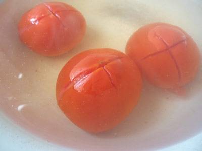 Далее их необходимо очистить от кожицы, а чтобы это было проще сделать, помидоры необходимо бланшировать. Итак, делаем на помидорах крестообразные надрезу, опускаем их в кипяток на 2-3 минуты, затем перекладываем на пару минут в холодную воду.