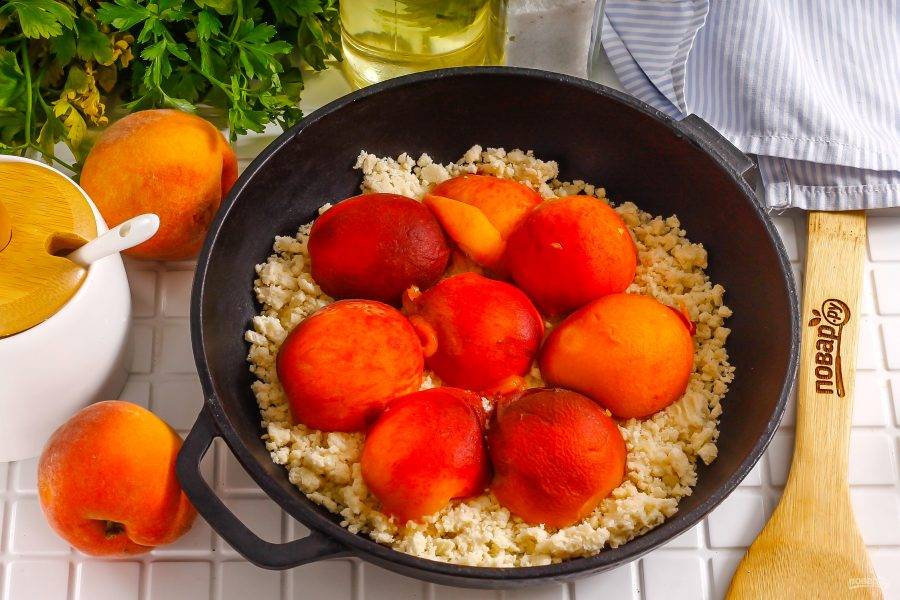 На тесто выложите половинки персиков.