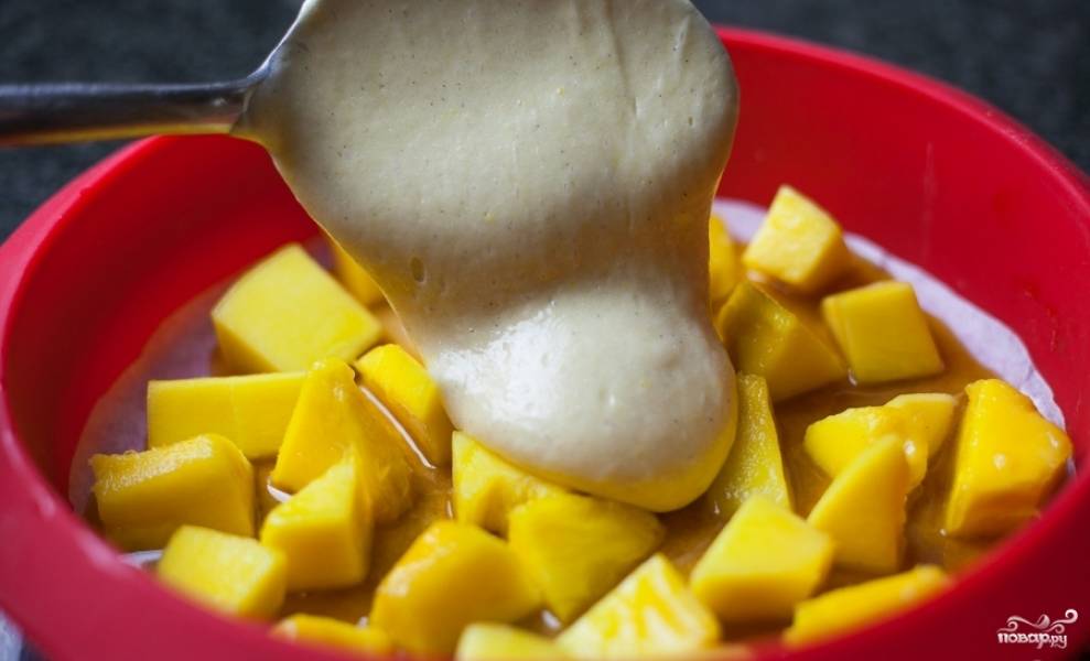 Выложите кубики манго в форму для выпекания. И залейте тестом.