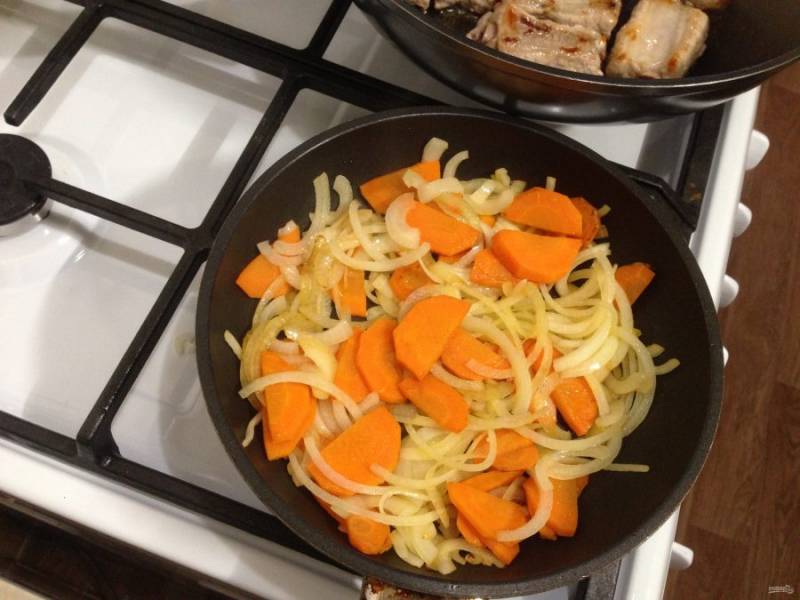Пока ребрышки обжариваются, на другой сковороде начинаем обжаривать морковь. Пусть она немного притушится. После чего добавляем к ней лук.