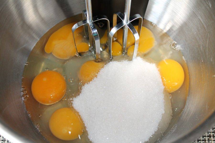 В чашу миксера выложите желтки, и вбейте яйца. Затем всыпьте в чашу сахар.