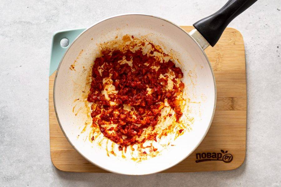 В сковороде обжарьте мелко нарезанный репчатый лук, затем добавьте томатную и все специи. Потушите все вместе еще 1-2 минуты.