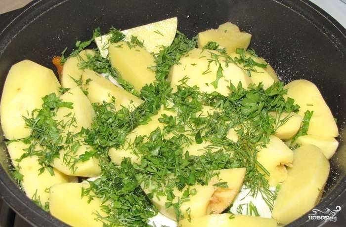 Очистите и тщательно вымойте картофель. Клубни порежьте на крупные куски и уложите поверх капусты. Посолите сверху. Затем присыпьте остатком зелени. 