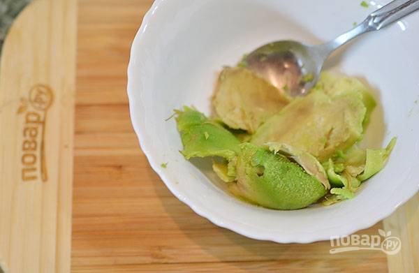 Мякоть авокадо выскребите ложкой, добавьте лимонный сок и разомните.