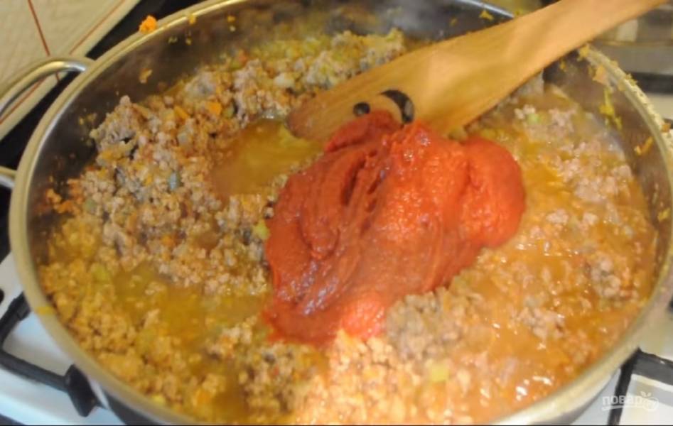 3. Тушите все 5 минут. После этого добавьте томатную пасту и перемешайте. Добавьте кипяток так, чтобы уровень жидкости был вровень с ингредиентами. Добавьте соль по вкусу, а также пару лавровых листков. Убавьте огонь, накройте крышкой и тушите примерно 1,5 часа. В результате получится густой соус.