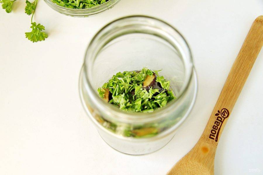 Выложите баклажаны в стерилизованные баночки слоями, чередуя каждый слой смесью из зелени и чеснока.