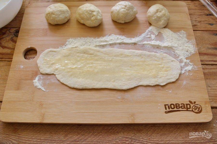 Разделите тесто на 6 частей. Из каждой части скатайте колбаску, которую потом раскатайте в тонкий овал. Растопите сливочное масло и при помощи кисточки смажьте тесто с одной стороны маслом.