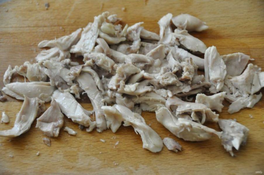 Извлеките из готового бульона курицу, отделите мясо от костей, измельчите его и верните снова в кастрюлю.