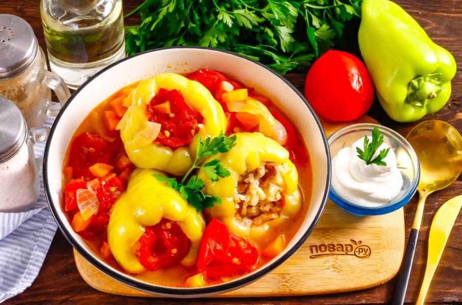 Выложите фаршированные перцы в тарелку, залейте томатным бульоном и подайте к столу горячими, не забыв про сметану.