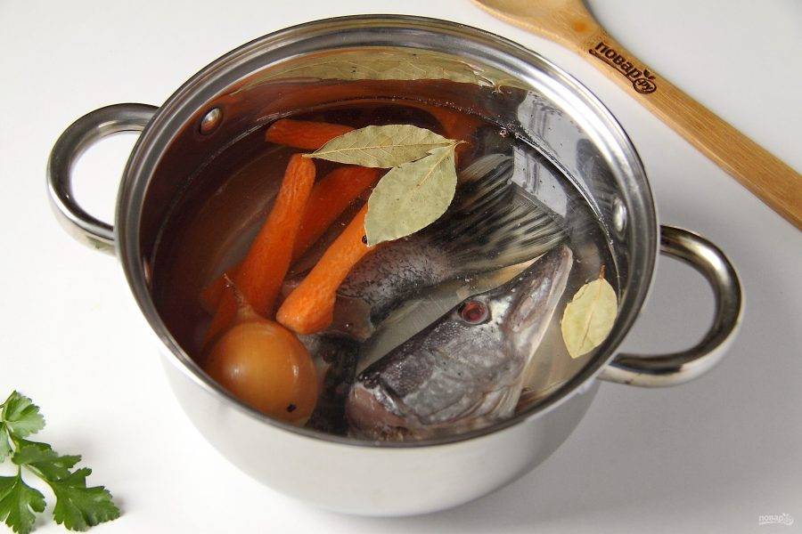 Для того, чтобы приготовить уху, необходимо сварить наваристый и ароматный бульон. Если вы используете целую тушку рыбы, то выпотрошите ее, почистите если необходимо и промойте. Отрежьте голову, хвост и плавники. Налейте в кастрюлю воду, добавьте соль, лавровый лист, перец горошком, одну луковицу с одним слоем шелухи и нарезанную морковь.