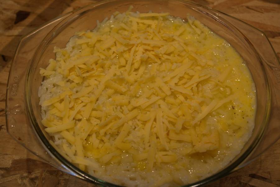 Полученную яичную массу вылейте на рис. Натрите на терке твердый сыр. Распределите сыр равномерно. Разогрейте духовку до 200 градусов. Запекайте рис в духовке около 20 минут.