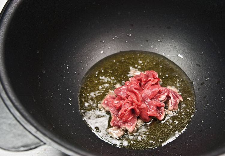 Разогрейте глубокую сковороду, влейте оливковое масло, обжарьте первую половину говядины. Сильно обжаривать не стоит.