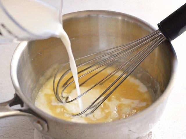 3.	К золотистой массе в сотейник влейте тонкой струйкой молоко, все время перемешивая венчиком.