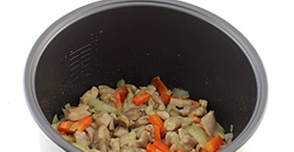 Затем добавьте лук и морковь. Обжаривайте курицу с овощами в течение 10 минут.