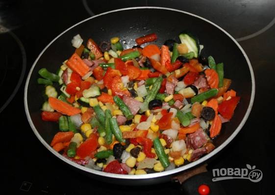1.	Сковороду разогрейте с растительным маслом, затем выложите замороженную овощную смесь и обжаривайте, добавьте измельченную колбасу. Обжаривайте овощи до готовности под закрытой крышкой (10-15 минут), посолите.