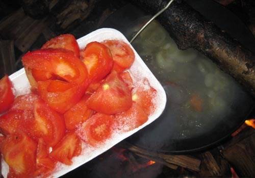 Через 30 минут добавляем в казан помидоры, порезанные четвертинками и очищенные от кожицы.