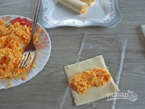 На пластинку плавленого сыра выкладываем начинку и заворачиваем сыр с начинкой в трубочку.