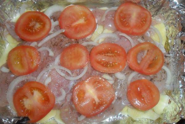 На мясо с луком выложите тонко нарезанные помидоры.
