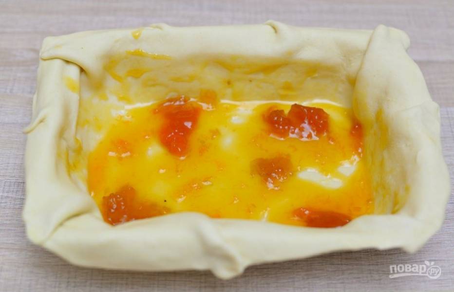 4. Раскатайте тесто и выложите его в глубокую форму для выпечки, сверху смажьте абрикосовым вареньем.