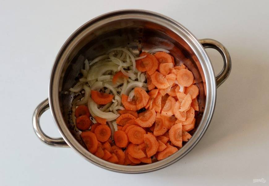 В кастрюле нагрейте растительное масло, обжарьте специи до раскрытия аромата. Лук нарежьте полукольцами, морковь кружочками. Обжаривайте овощи примерно 3-4 минуты.