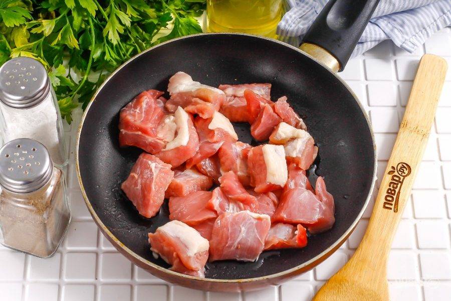 Мясо промойте в воде, срежьте кожу и пленки, жилы, если они присутствуют. Нарежьте порционными кусочками среднего размера. Если хотите приготовить блюдо быстрее, то нарежьте мелко. Раскалите в сковороде растительное масло, и обжарьте в нем мясную нарезку примерно 10-15 минут на умеренном нагреве. Сначала мясо выделит сок, затем он выпарится и свинина начнет подрумяниваться.