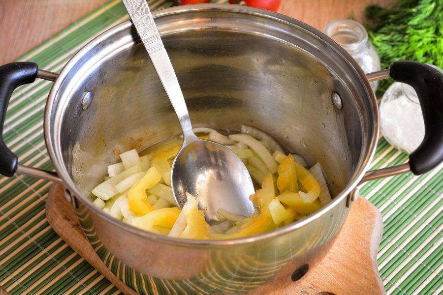 Влейте в кастрюлю масло и обжарьте в нем лук и сладкий перец, нарезанные полосками. Перец можно использовать как красный, так и желтый или зеленый. Обжаривайте овощи 3-4 минуты, постоянно помешивая.