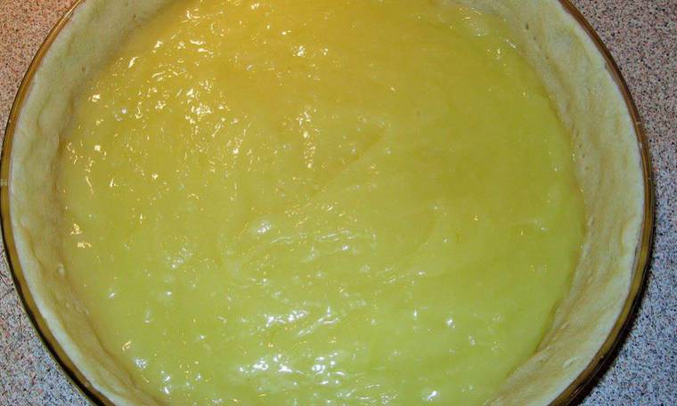 В кастрюлю вливаем 250 мл воды и лимонный сок с крахмалом. Ставим на огонь и помешивая доводим до кипения. Добавляем: 3 яичных желтка, ванилин по вкусу, лимонную цедру, сахар и 100 грамм сливочного масла. Снова кипятим и доводим массу до загустения (консистенция, как заварной крем). Массу остудить и вылить на тесто.

