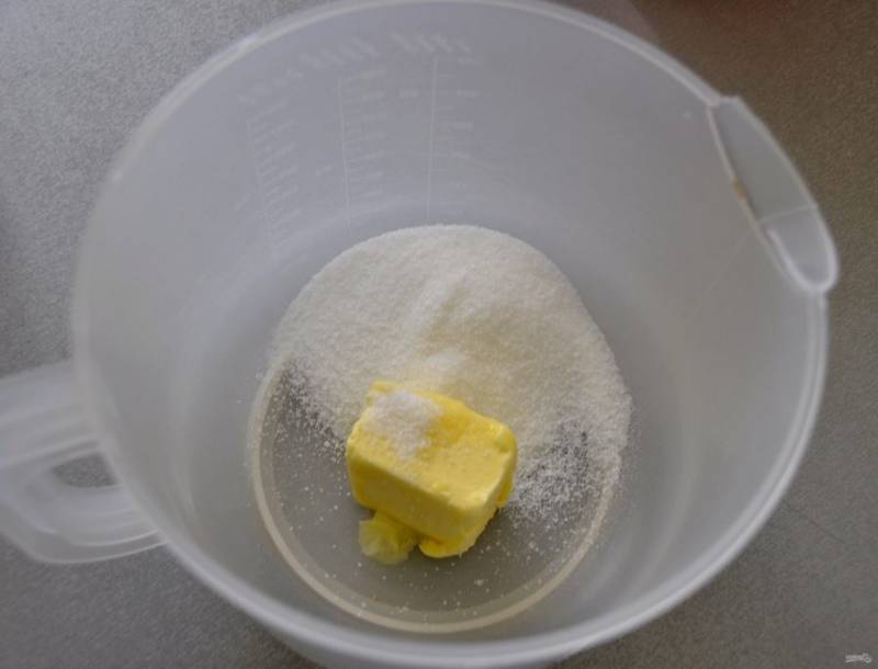В емкость для взбивания выложите 50 грамм размягченного сливочного масла и 50 грамм сахарного песка.