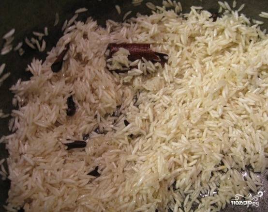 Теперь всыпаем рис, перемешиваем и жарим несколько минут. Затем вливаем 1,5-2 стакана кипятка и варим рис на среднем огне 8-10 минут под закрытой крышкой.